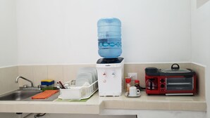 Une cuisine équipée d’un distributeur d’eau, d’une machine à café et d’une bouilloire électrique rouge.