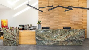 Un mostrador de recepción con encimera de mármol, pared de paneles de madera e iluminación colgante.