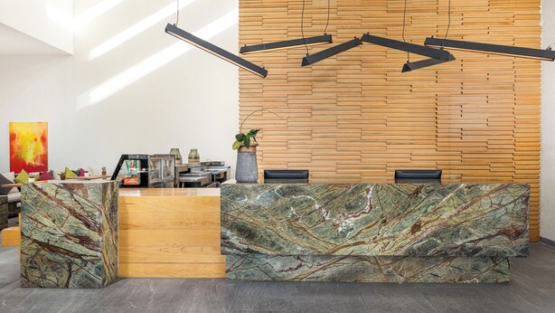 A reception desk with a marble top, wooden panel wall, and pendant lighting. - Hotel México Plaza Querétaro (Querétaro)
