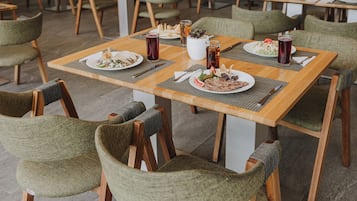 Un comedor con mesas de madera y sillas tapizadas en verde.