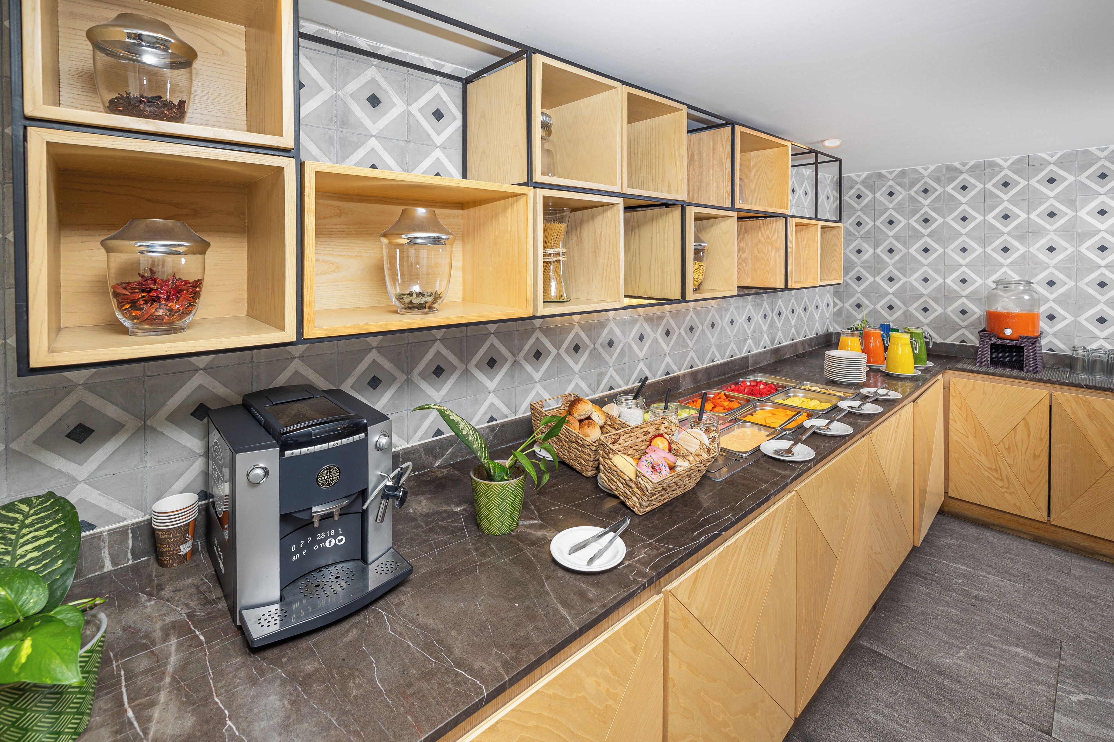 Una cocina con estantes de madera, una máquina de café y una zona de bufé con diferentes alimentos.