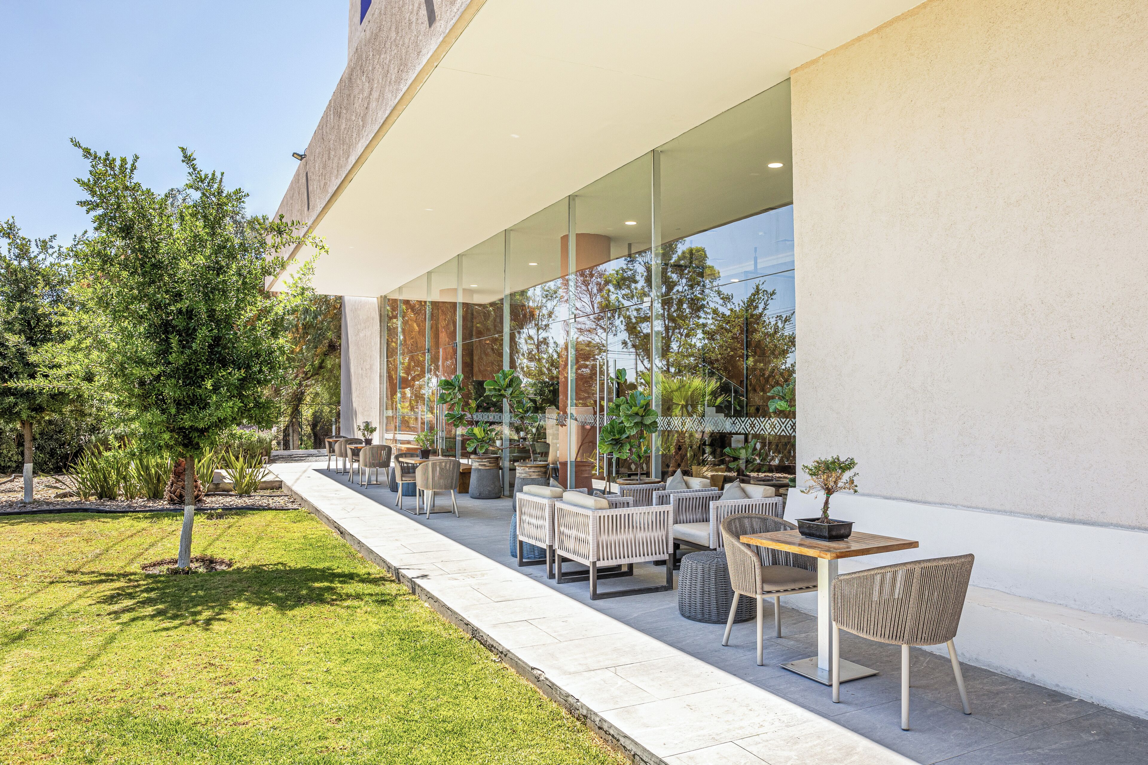 Un espace extérieur aménagé avec des meubles modernes, un chemin et un bâtiment doté de grandes fenêtres.