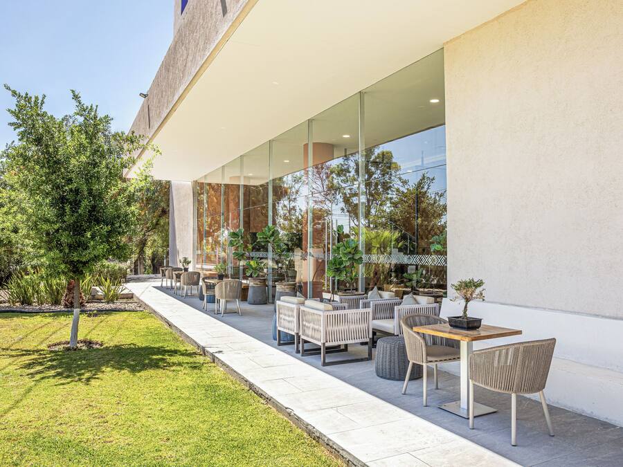 An outdoor seating area with modern furniture, a pathway, and a building with large windows.