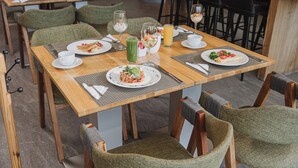 Un comedor con mesas de madera, sillas tapizadas de verde y diversos platos y bebidas.
