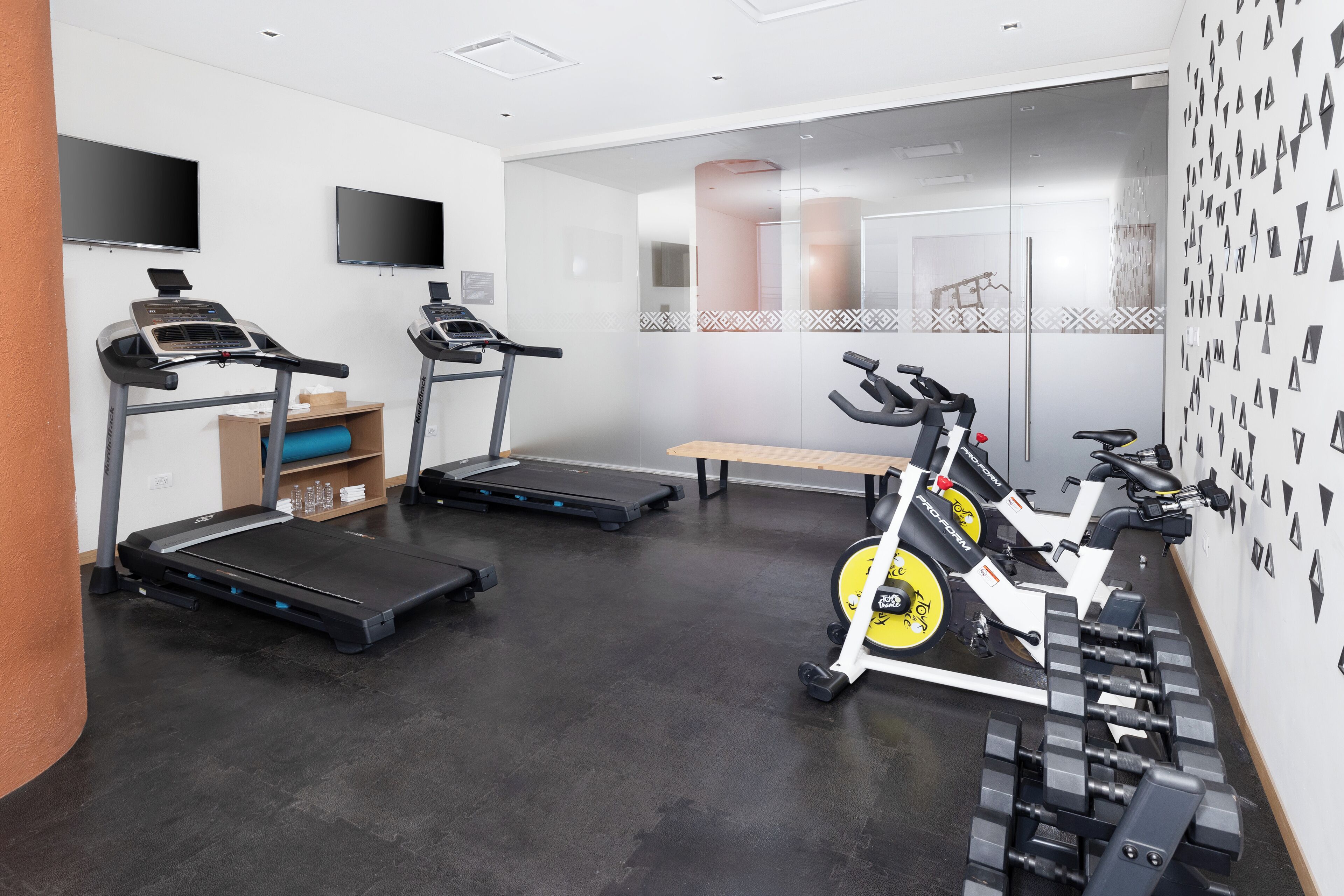A gym with treadmills, an elliptical, and dumbbells.