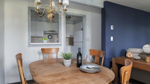 A dining area with a wooden table, chairs, a chandelier, a potted plant, a wine bottle, and a clock on the wall. - Outpost: Gros Ventre A8 - Hot Tub Access (Teton Village)
