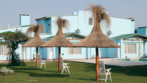 A resort with thatched umbrellas, lounge chairs, and a pool area. - Apart No Me Olvides (Federacion)