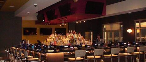 A bar area with multiple seating arrangements and a well-stocked bar counter.