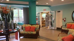 A lobby with wicker furniture, a reception desk, and a display of sunglasses.