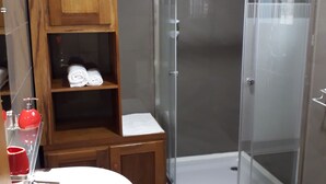 Een moderne badkamer met een douchecabine van glas, houten kastjes en een witte wastafel.