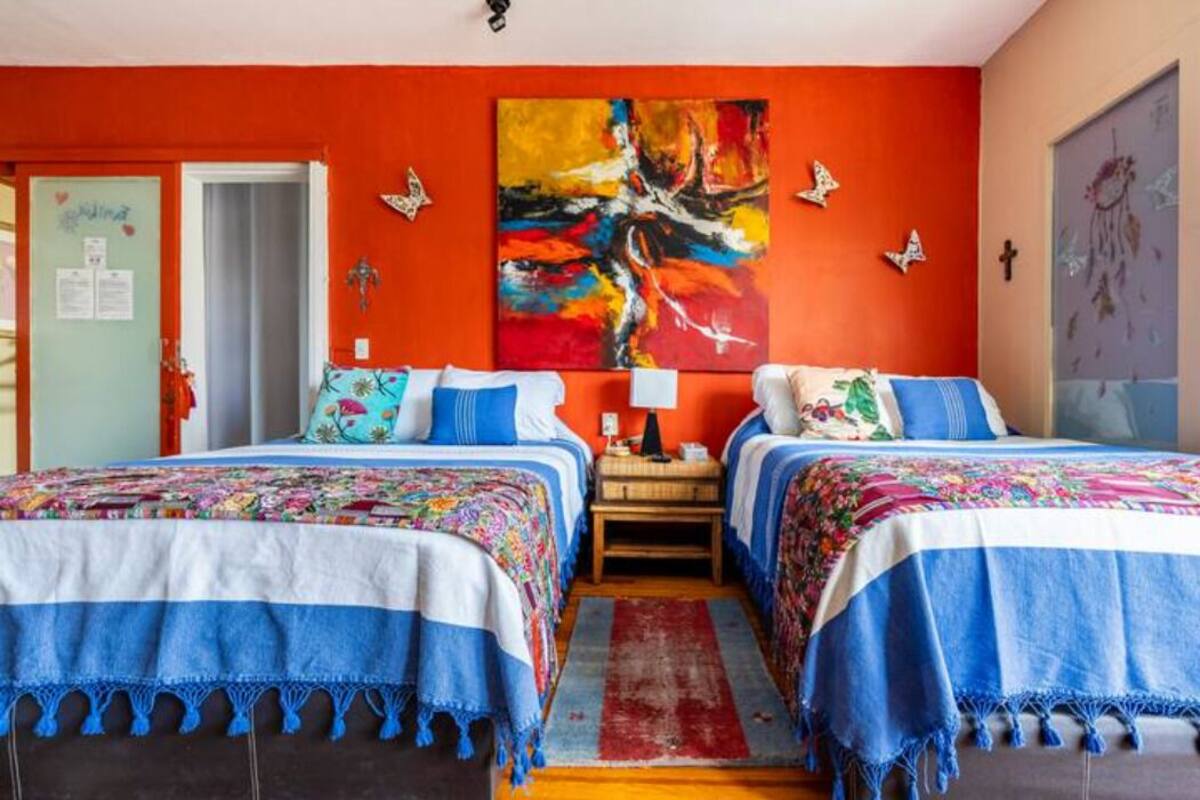 A room with two beds, a colorful abstract painting, and butterfly wall decorations.