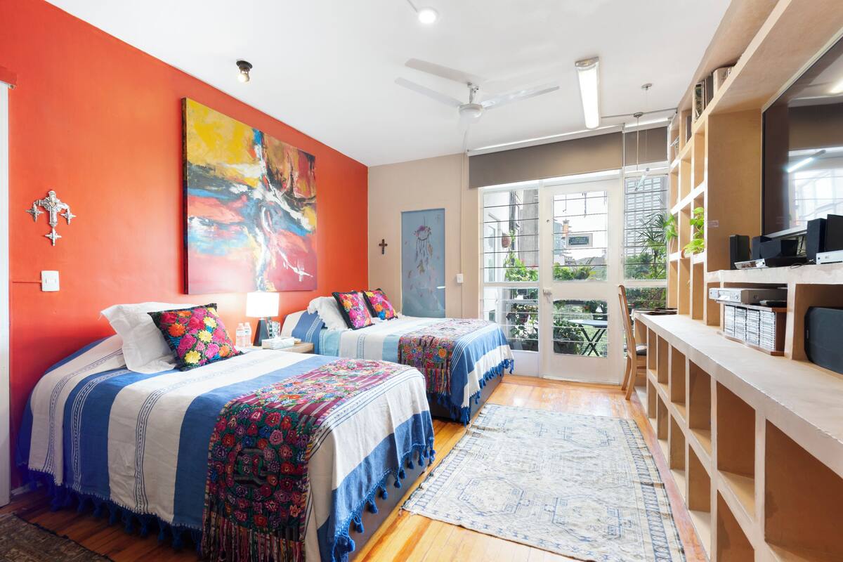 A modern bedroom with two beds, a large window, and a balcony.