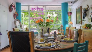 A dining area with a table set for a meal, chairs, a vase with flowers, and a window with greenery outside. - Casa Itzae B&B Polanquito Dog Friendly (Mexico City)