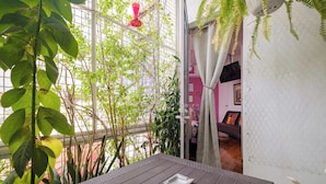A balcony with a wooden table, a white wall, and a view of a pink interior. - Casa Itzae B&B Polanquito Dog Friendly (Mexico City)