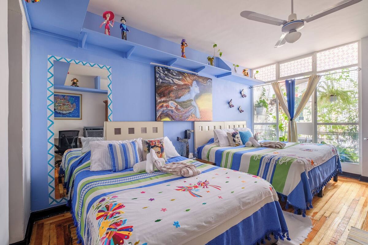 A hotel room with two beds, blue walls, and a ceiling fan.