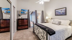 Een slaapkamer met een bed, een kaptafel, een dressoir, een plafondventilator en een raam met gordijnen.