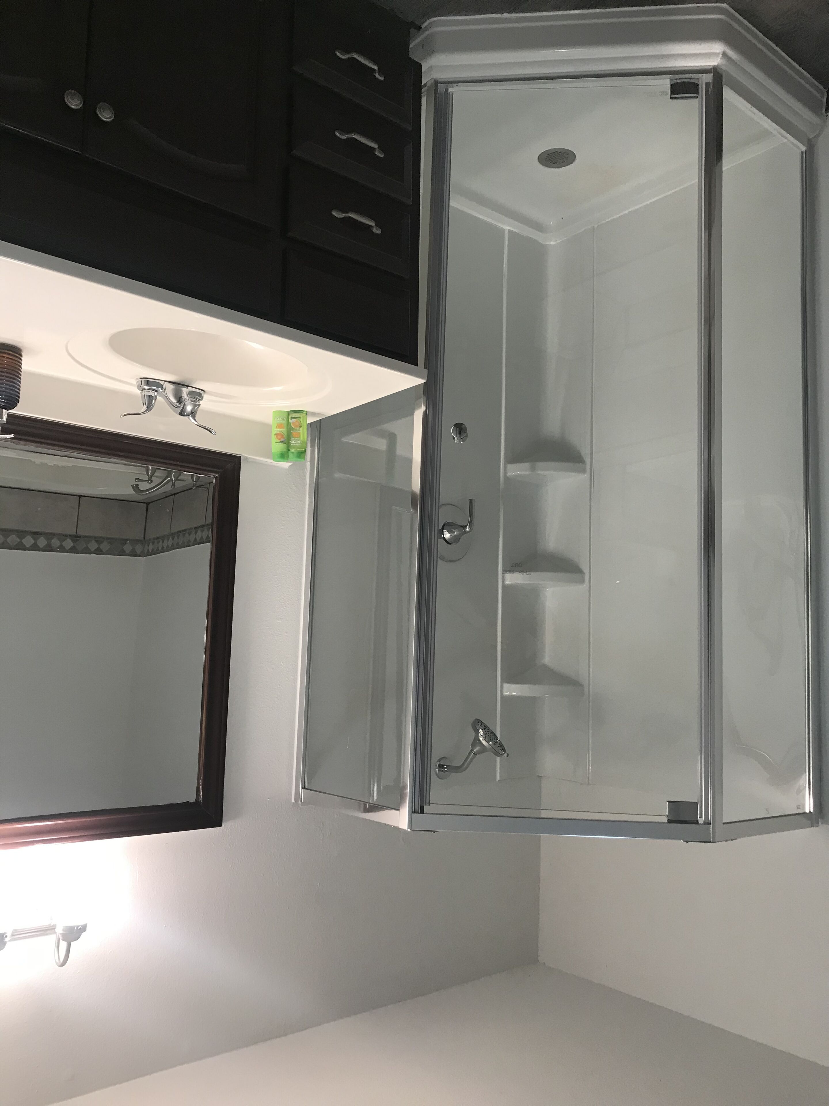 Une salle de bain avec une douche à parois de verre, un lavabo et un miroir.