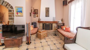 Un salon chaleureux avec une cheminée, un téléviseur et des fauteuils confortables.