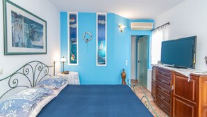 Une chambre à coucher avec un grand lit, une commode, un téléviseur et des œuvres d’art murales.