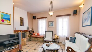 Un salon avec un téléviseur, un canapé, un fauteuil et une cheminée.