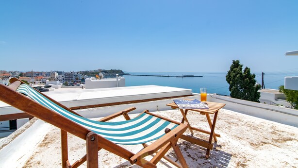 Une terrasse sur le toit avec un hamac, une petite table et un verre de jus d’orange.