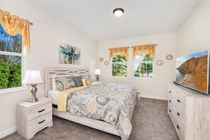 A bedroom with a bed, a nightstand, a dresser, and a television.