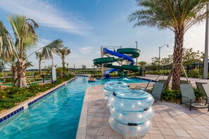 A swimming pool with a water slide, lounge chairs, and palm trees. - Storey Book Dreams by VillaDirect (Kissimmee)