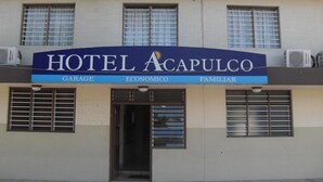 Un bâtiment sur lequel on peut lire l’inscription « HÔTEL ACAPULCO », et en dessous, trois mots : « GARAGE », « ÉCONOMIQUE » et « FAMILIAL ».
