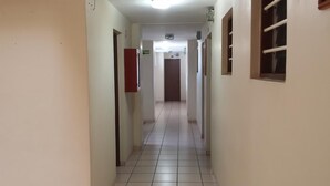 Un couloir aux murs blancs, au sol carrelé et dont les deux côtés sont bordés de portes.