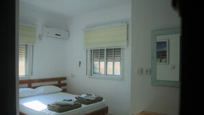 Un dormitorio con cama, escritorio y ventana.