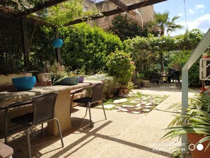 An outdoor patio area with a stone table and chairs, surrounded by potted plants and greenery. - David Hostel - Hostel (Tiberias)