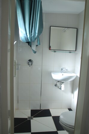 A bathroom with a white sink, a mirror, and a shower. - David Hostel - Hostel (Tiberias)