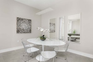 Un comedor moderno con una mesa redonda, sillas de malla metálica y arte abstracto en la pared.