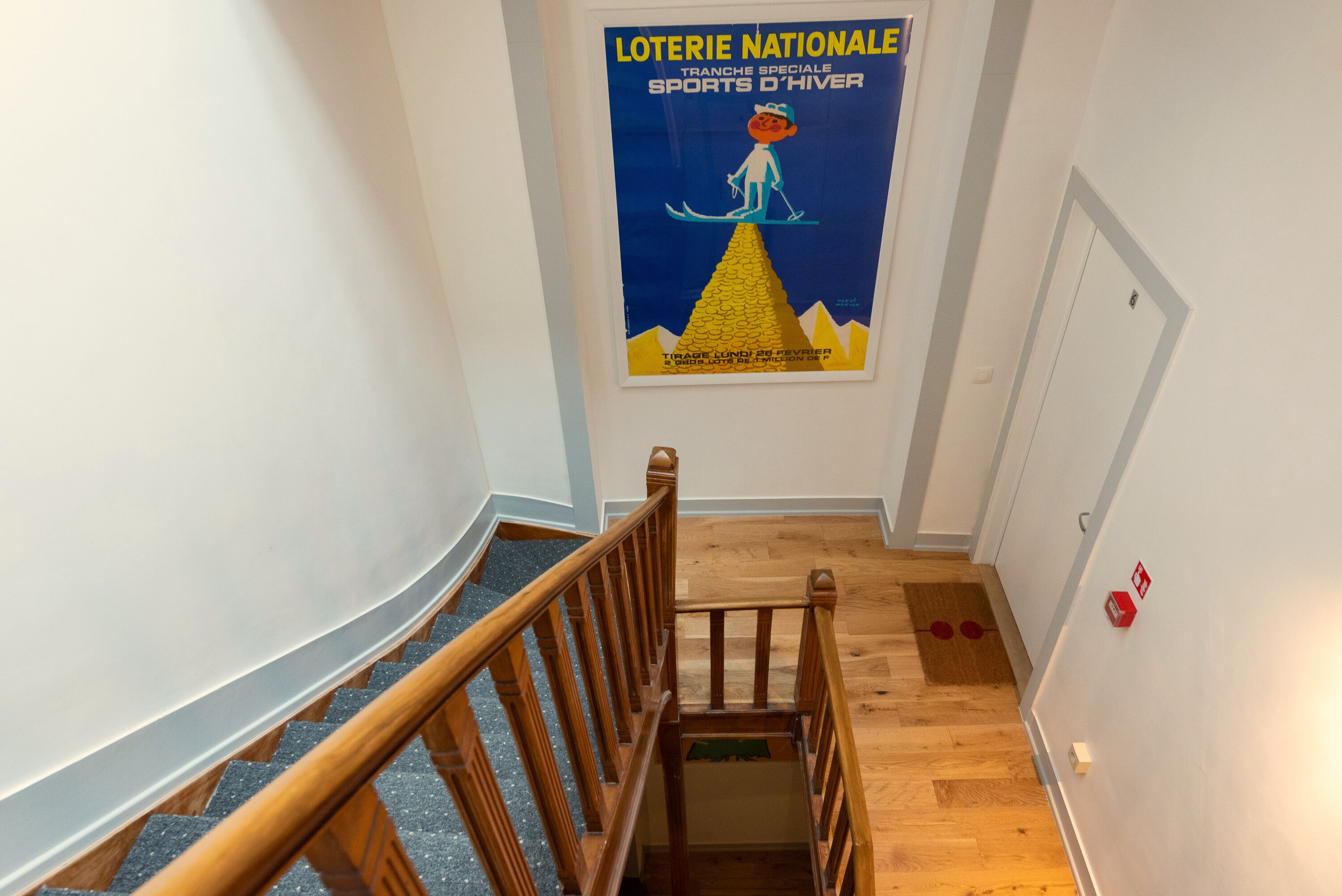 A staircase with wooden railings and a poster on the wall advertising a winter sports event.