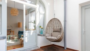 A modern interior with a hanging chair, a glass table, and a sofa. - Europea Newton Boutique Hotel Residences (Brussels)
