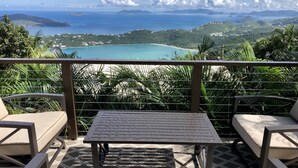 A terrace with a table and chairs, overlooking a coastal landscape with mountains and a turquoise sea. - Virgin Island Villa Suite, View, Private Pool & Hot Tub! (St. Thomas)