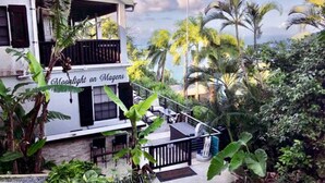 A two-story building with a balcony, surrounded by tropical vegetation and an American flag. - Virgin Island Villa Suite, View, Private Pool & Hot Tub! (St. Thomas)