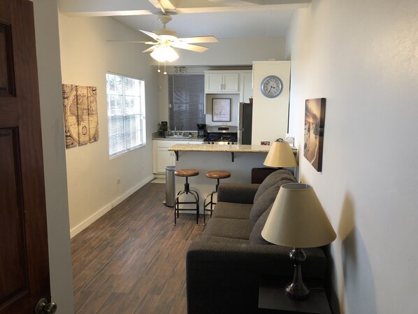 A compact kitchen with a central island, a ceiling fan, and a clock on the wall.