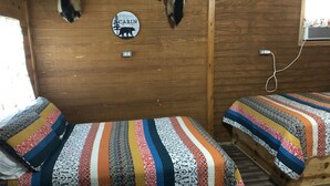 A cabin interior with two beds, a welcome sign, and mounted animal heads on the wall. - Our cabins are located on the crystal clear water of Spring Creek. (Mertzon)