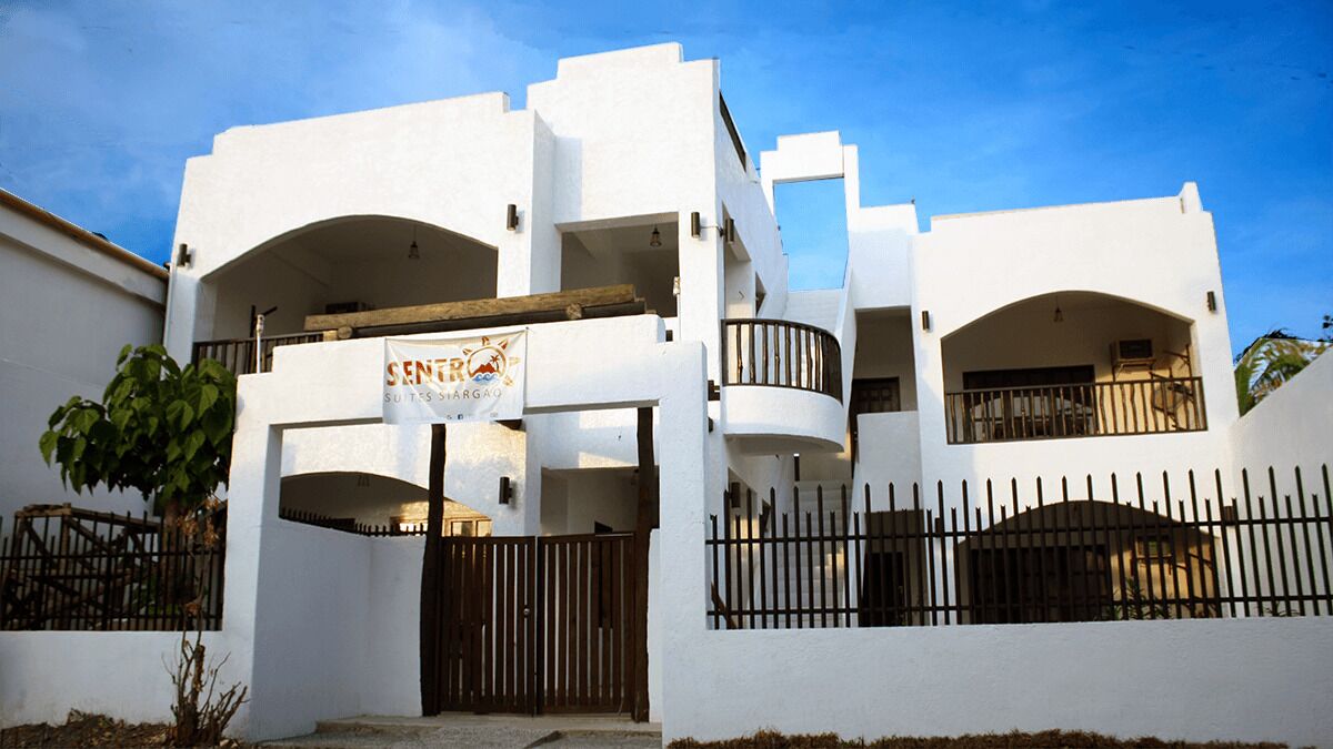 Een wit gebouw met een bord waarop staat 'SENTRO SUITES SARGAO'.