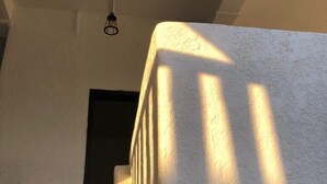 A corner of a room with a textured wall and a door frame casting a shadow. - Sentro Suites Siargao (General Luna)