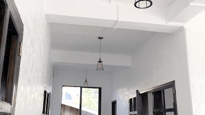 A room with white walls, a large window, and a hanging light fixture. - Sentro Suites Siargao (General Luna)