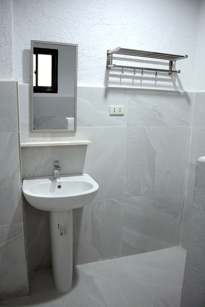 A bathroom with a white pedestal sink, a mirror, and a towel rack.