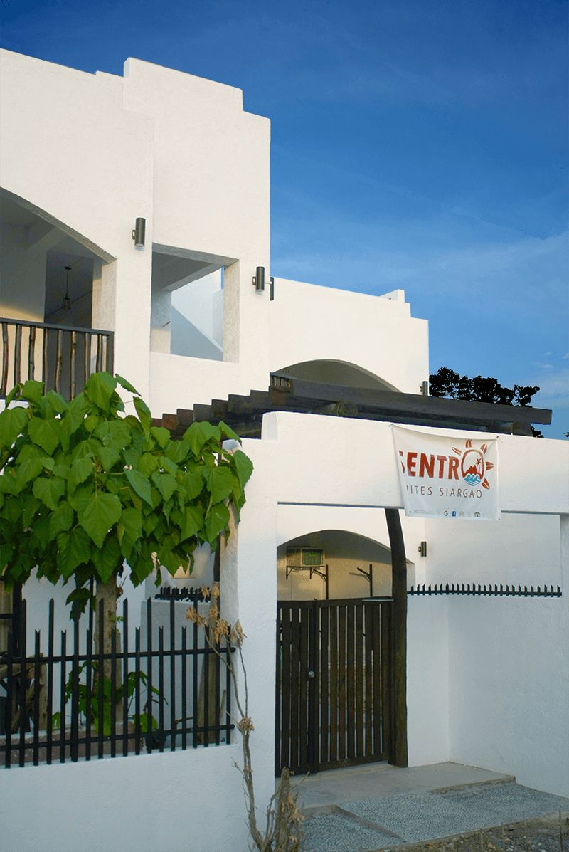 A white building with a sign reading "ENTRÓ GITES SIARGAO".
