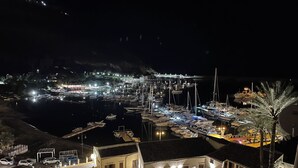 A marina at night with boats docked, a building with a balcony, and a staircase leading to the upper floor. - Suite de la Sicilienne Deluxe in the center near the port and 200 mt from the sea (Castellammare del Golfo)