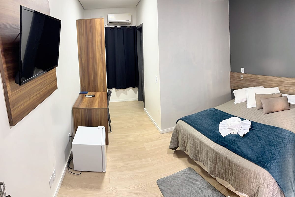Ein Hotelzimmer mit Bett, Nachttisch, Fernseher, Kleiderschrank und Klimaanlage.