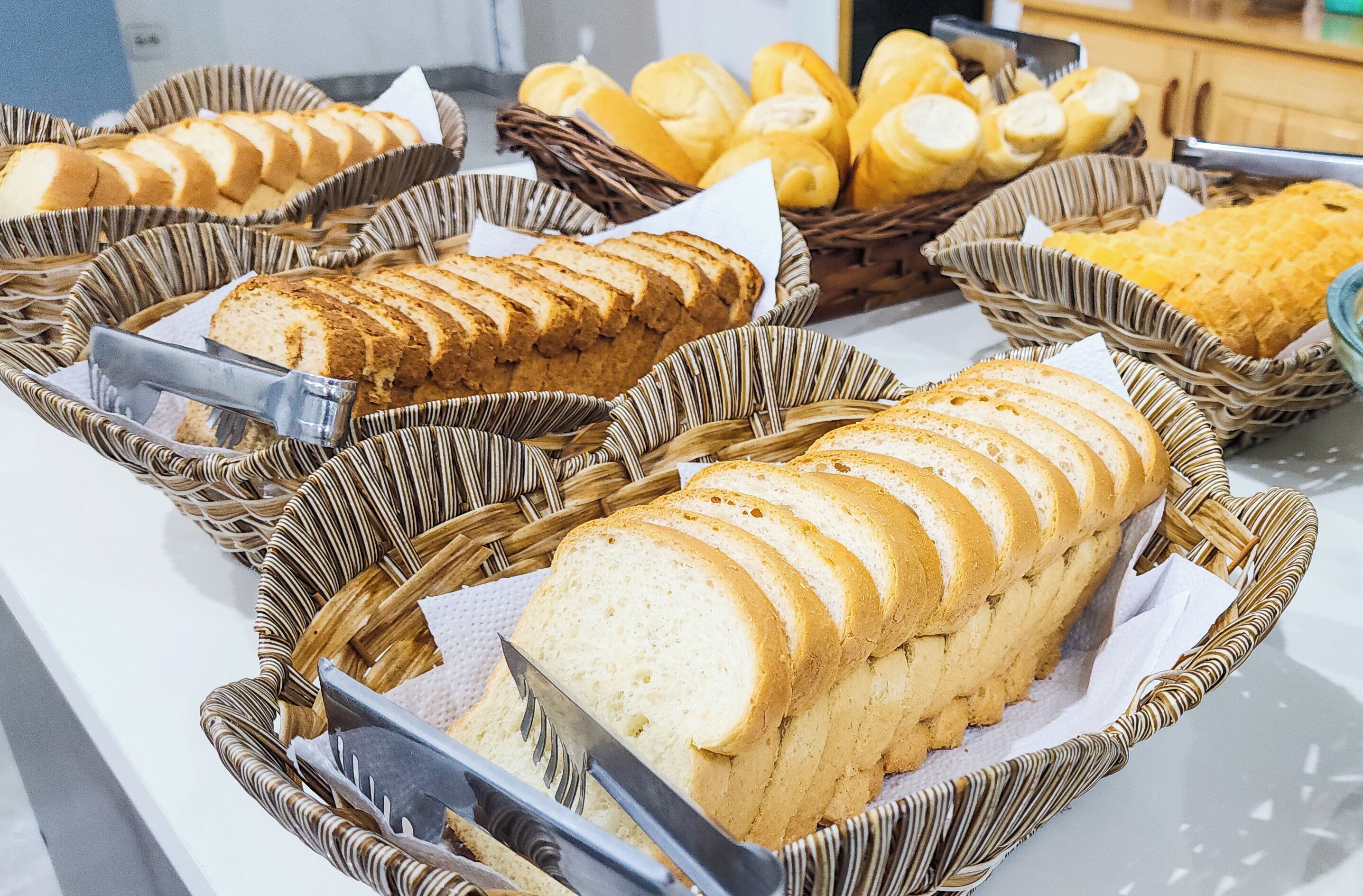 A buffet with various breads and pastries displayed in wicker baskets.