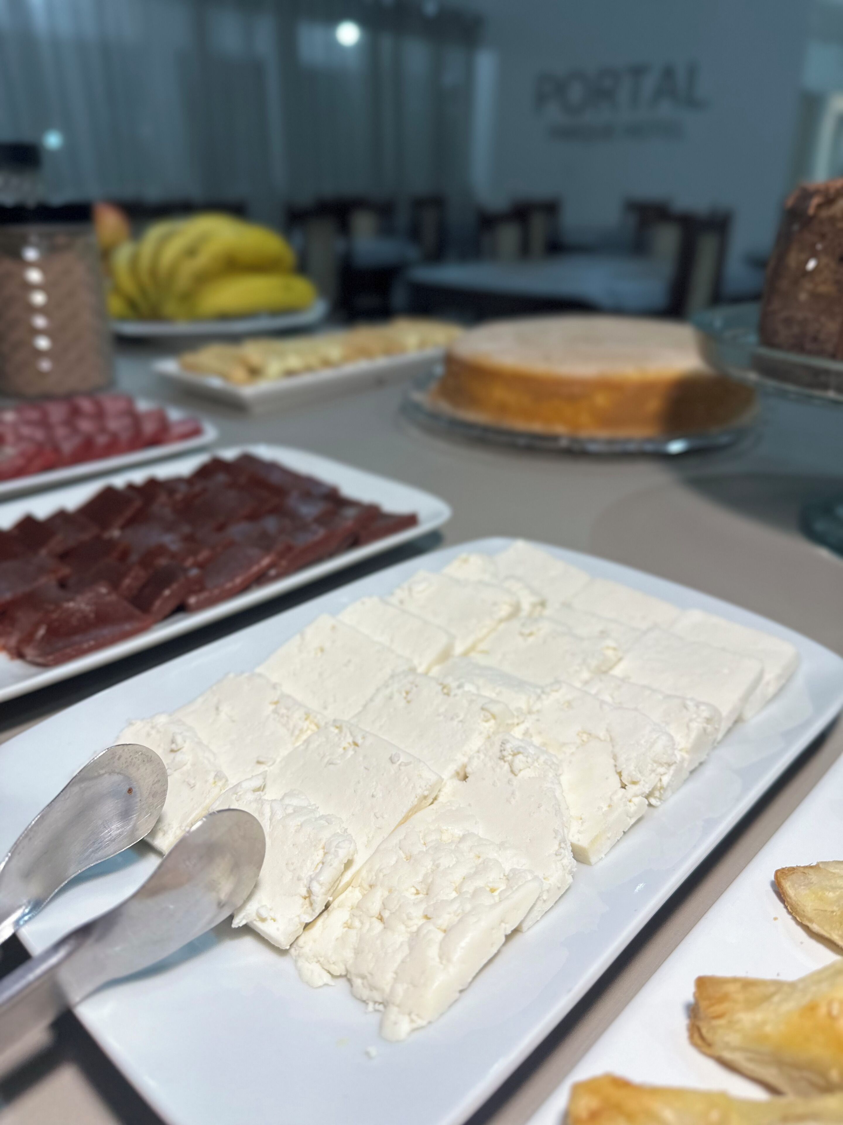 Una mesa de buffet con diversos alimentos, incluyendo queso blanco, carne roja y un pastel.