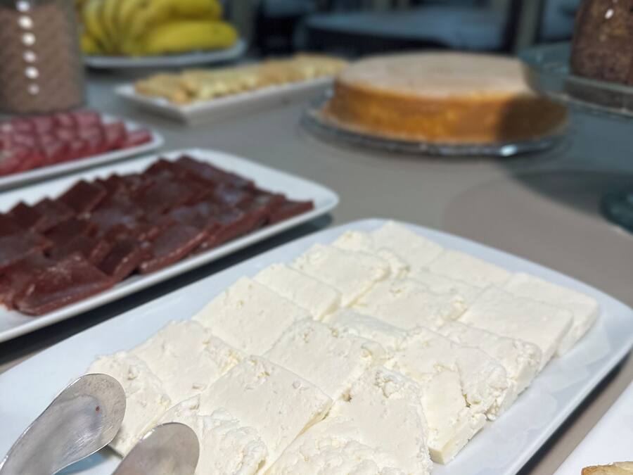 Una mesa de buffet con diversos alimentos, incluyendo queso blanco, carne roja y un pastel.