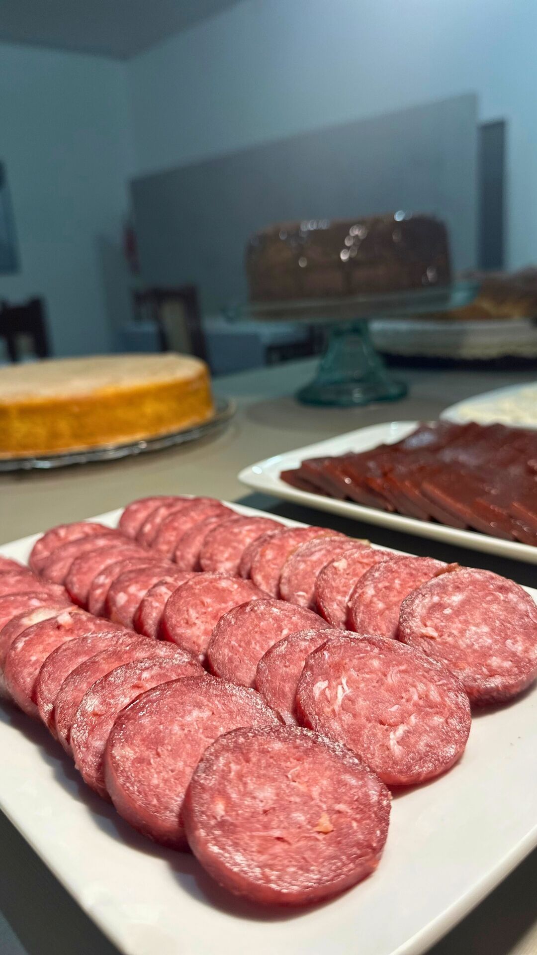 Un plato de salami en rodajas y un pastel sobre una mesa.